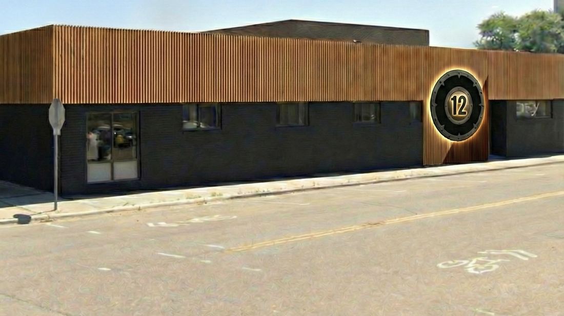 The Nordic Zone building exterior — dark brick with wood slat detailing and the lit shield sign